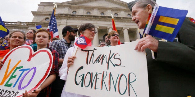 Kristen Hooper, center, and Robert Loyd, right, hold a sign on the steps of the Arkansas state Capitol thanking Arkansas Gov. Asa Hutchinson for calling for changes to a religious objection measure in Little Rock, Ark., Wednesday, April 1, 2015. The measure faced a backlash from businesses and gay rights groups. (AP Photo/Danny Johnston)