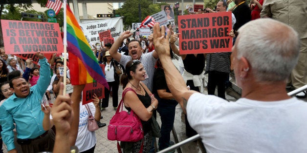 MIAMI, FL - JULY 02: Opponents of same-sex marriage yell at Howard Brownstein, who is showing them his wedding ring, as he shows his support in front of the Miami-Dade Courthouse for the LGBTQ couples inside the courthouse are asking the state of Florida to recognize their marriage on July 2, 2014 in Miami, Florida. Six couples that identify as Lesbian, Gay, Bisexual, Transgender and Queer (LGBTQ) are in court asking that their same-sex marriage be recognized in the state of Florida. (Photo by Joe Raedle/Getty Images)