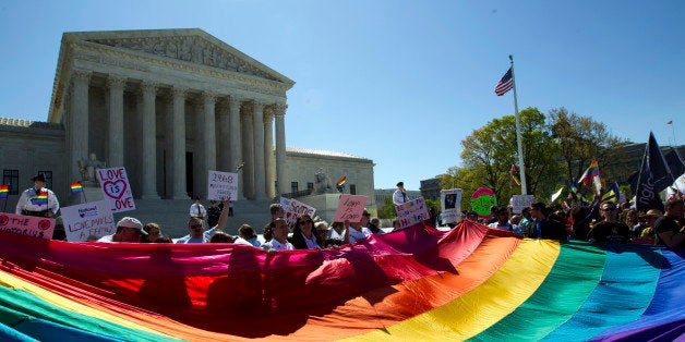 Demonstrators stand in front of a rainbow flag of the Supreme Court in Washington, Tuesday, April 28, 2015. The Supreme Court is set to hear historic arguments in cases that could make same-sex marriage the law of the land. The justices are meeting Tuesday to offer the first public indication of where they stand in the dispute over whether states can continue defining marriage as the union of a man and a woman, or whether the Constitution gives gay and lesbian couples the right to marry. (AP Photo/Jose Luis Magana)