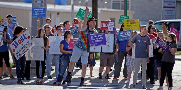 Same-sex marriage supporters hold signs encouraging drivers to honk in support of marriage equality during a rally Tuesday, April 28, 2015, in Salt Lake City. Supporters and opponents of same-sex marriage rallied in Utah on Tuesday after the U.S. Supreme Court heard arguments on the constitutionality of laws banning such marriages. Opponents of gay marriage will hold a rally at Utah's state Capitol Tuesday night. (AP Photo/Rick Bowmer)