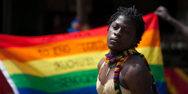A transgender Ugandan poses in front of a rainbow flag during the 3rd Annual Lesbian, Gay, Bisexual and Transgender (LGBT) Pride celebrations in Entebbe, Uganda, Saturday, Aug. 9, 2014. Scores of Ugandan homosexuals and their supporters are holding a gay pride parade on a beach in the lakeside town of Entebbe. The parade is their first public event since a Ugandan court invalidated an anti-gay law that was widely condemned by some Western governments and rights watchdogs. (AP Photo/Rebecca Vassie)