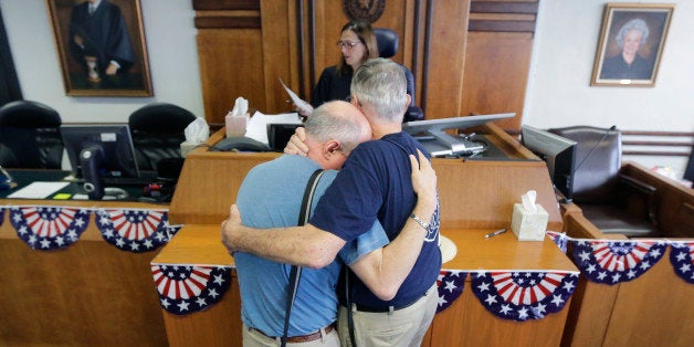 Gerald Gafford, right, comforts his partner of 28 years, Jeff Sralla, left, as they stand before Judge Amy Clark Meachum to receive obtain a time waiver at the Travis County Courthouse after the U.S. Supreme Court ruled that same-sex couples have the right to marry nationwide, Friday, June 26, 2015, in Austin, Texas. The court's 5-4 ruling means the remaining 14 states, in the South and Midwest, will have to stop enforcing their bans on same-sex marriage. Sralla broke into tears as the judge approved the waiver allowing the couple to get married this weekend. (AP Photo/Eric Gay)