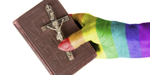 Hand (woman) holding a very old bible, isolated on white, rainbow flag