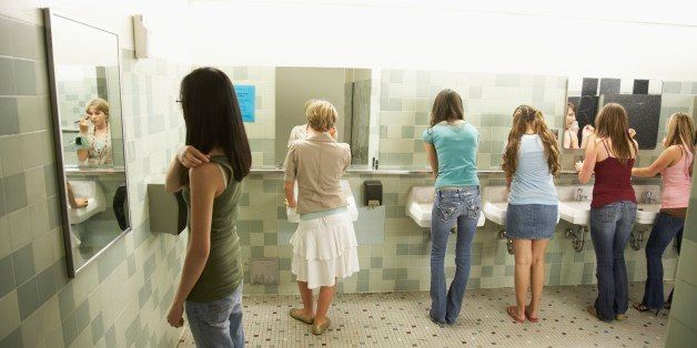 Group of teenaged girls using mirrors in school bathroom