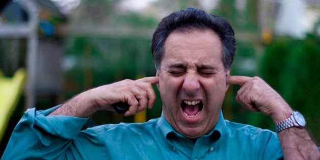 Man with fingers in his ears screaming.