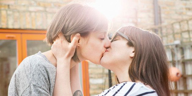 lesbian couple kissing in garden.