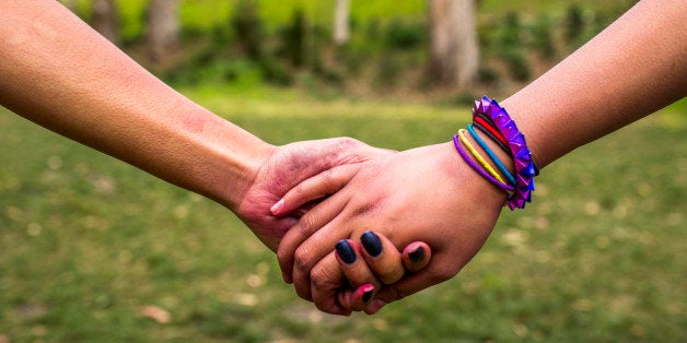 Close up of women holding hands in park