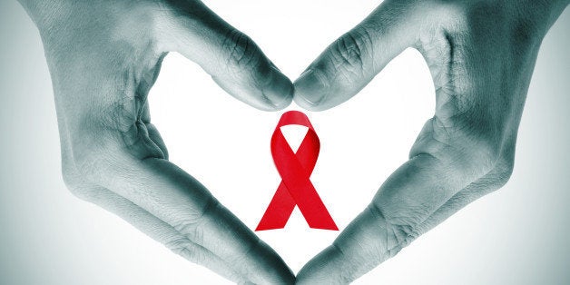 man hands forming a heart with his hands and a red ribbon for the fight against AIDS on a white background