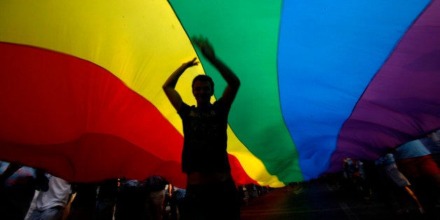 A gay rights activist dances under a rainbow flag during the Gay Pride parade in downtown Athens, on Saturday, June 4, 2011.