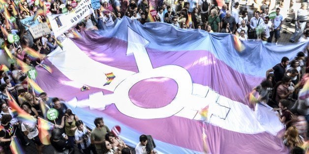 People hold a giant transgender flag during a gay parade on Istiklal Street, the main shopping corridor in Istanbul, on June 22, 2014, during the Trans Pride Parade as part of the Trans Pride Week 2014, which is organized by Istanbul's 'Lesbians, Gays, Bisexuals, Transvestites and Transsexuals' (LGBTT) solidarity organization. AFP PHOTO/BULENT KILIC (Photo credit should read BULENT KILIC/AFP/Getty Images)