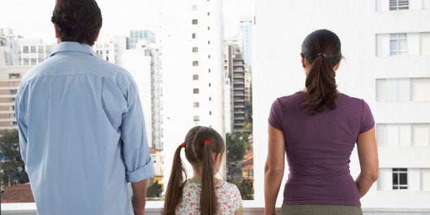 Parents and daughter (8-10) holding hands on balcony, rear view