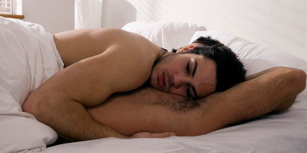 Gay man lying atop boyfriend in bed