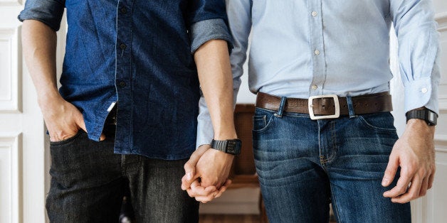 Close up shot of a gay couple holding hands. Focus on their hands.