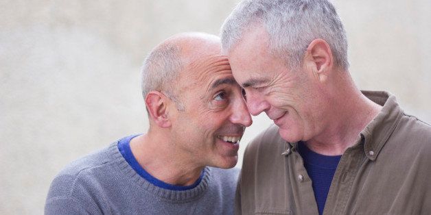 Senior mature older gay couple on vacation or honeymoon in European or American city smiling affectionately at each other
