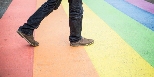 Netherlands, Maastricht, man walking on rainbow flag painted on the street