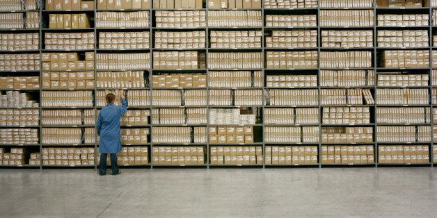 20 - 30 year old female worker pulls box off of warehouse shelf