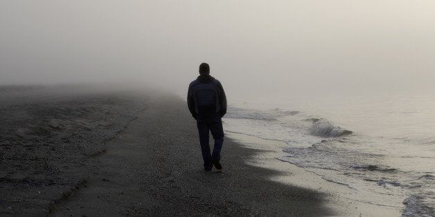 Lonely man walking on a foggy beach