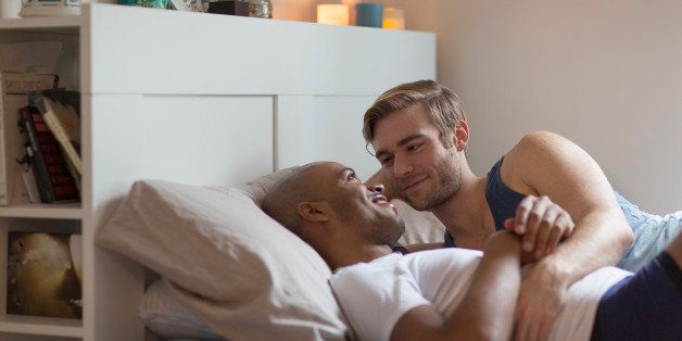 Male couple lying in bed together, face to face