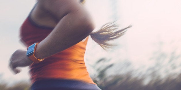 Woman running outdoor using a smart watch to track data.