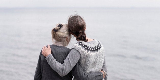 two generations women embracing, looking at sea