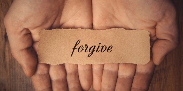 Hands holding piece of paper with word Forgive