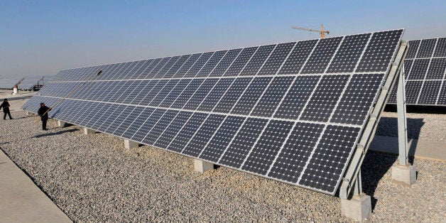 Workers clean solar panels at a solar energy plant in Jinzhou, Liaoning province December 12, 2009. Governments seeking to combat global warming are giving incentives for low-carbon energy production and penalizing industries that emit greenhouse gas emissions from fossil fuels. The global recession has curbed energy usage and reduced emissions but also scaled back investment in alternative energy. REUTERS/Sheng Li (CHINA - Tags: ENERGY ENVIRONMENT)