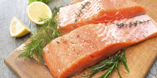 Raw salmon fish fillet with fresh herbs on cutting board