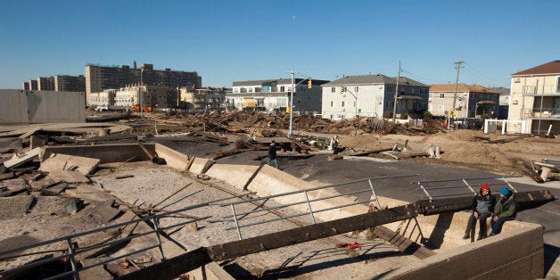 In this picture taken November 4, 2012 a couple sits amongst debris from a boardwalk damaged during Superstorm Sandy in the Rockaways neighborhood of the Queens borough of New York. The historic superstorm killed at least 159 people and damaged more than 650,000 homes when it made landfall on October 29, 2012, devastating parts of New York, New Jersey and several other states. TO MATCH ONE YEAR HURRICANE SANDY ANNIVERSARY BEFORE AFTER PACKAGE. Picture 18A. REUTERS/Lucas Jackson (UNITED STATES - Tags: ANNIVERSARY DISASTER ENVIRONMENT)