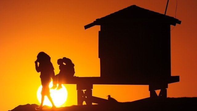 People view the setting sun from Seal Beach, south of Los Angeles on July 9, 2012 in California. Much of the US has been gripped by a relentless heatwave, sparking health warnings and sending people to makeshift cooling shelters, shopping malls and overcrowded swimming pools in search of relief. AFP PHOTO/Frederic J. BROWN (Photo credit should read FREDERIC J. BROWN/AFP/GettyImages)