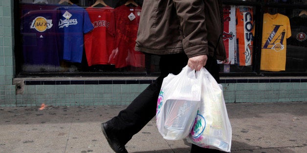 A man walks along the street with plastic bags in Los Angeles, Thursday, May 24, 2012. Now that the city of Los Angeles has taken the first step toward banning plastic bags, it appears the little utilitarian bags themselves may be headed for the trash heap of history. (AP Photo/Jae C. Hong)