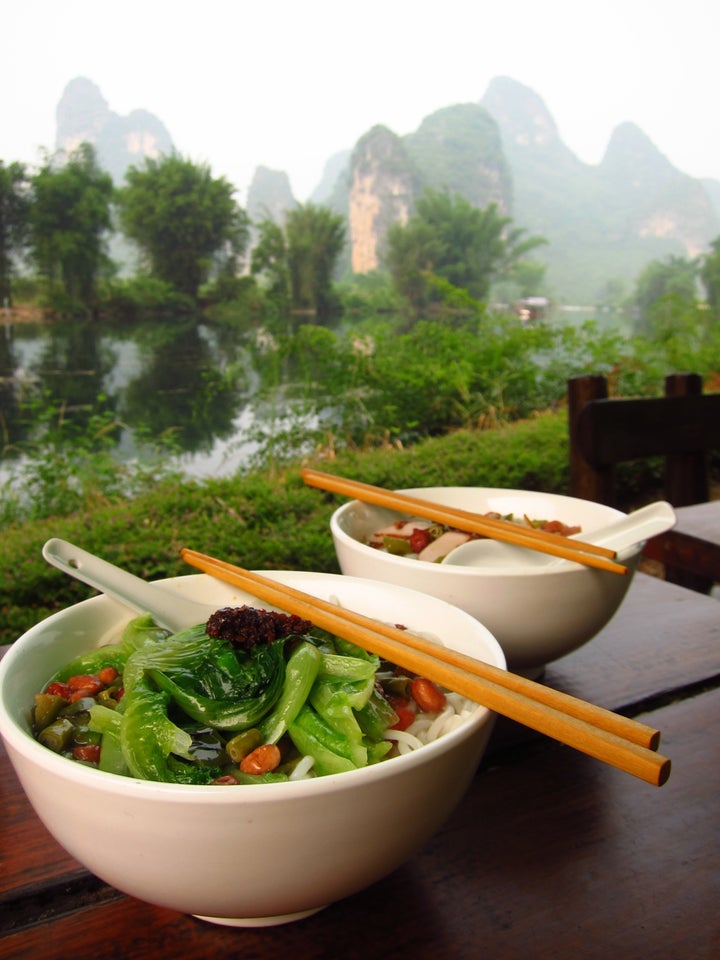 Bowl of round rice noodles with chopsticks and spoons on table in Yangshuo, China.