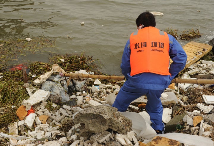 A sanitation worker collects a dead pig from Shanghai's main waterway on March 11, 2013. Nearly 3,000 dead pigs have been found floating in Shanghai's main waterway, the Chinese city's government said on March 11 as residents expressed fears over possible contamination of drinking water. AFP PHOTO/Peter PARKS (Photo credit should read PETER PARKS/AFP/Getty Images)