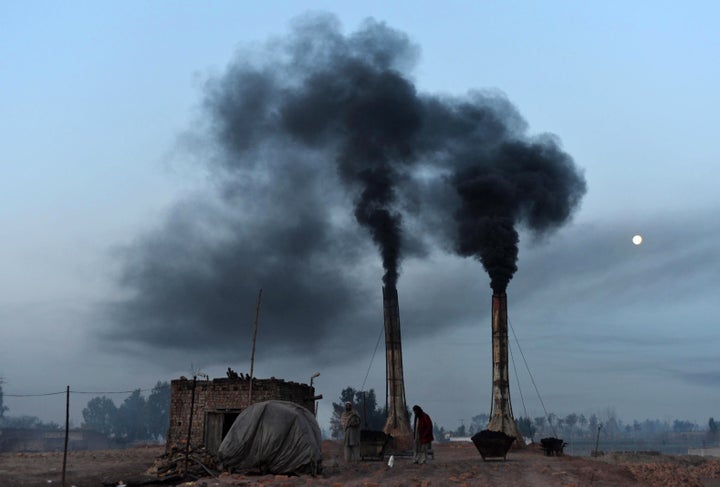 Labourers work as smoke rises from a brick kiln in Peshawar on January 30, 2013. AFP PHOTO/A MAJEED (Photo credit should read A Majeed/AFP/Getty Images)