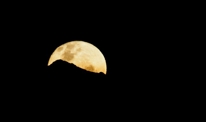 View of a full moon coming out behind the Central Andes, on March 27, 2013, in Cali, department of Valle del Cauca, Colombia. AFP PHOTO/Luis ROBAYO (Photo credit should read LUIS ROBAYO/AFP/Getty Images)