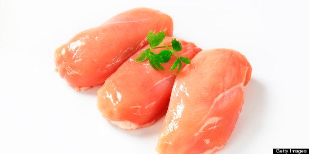 three pieces of raw chicken fillet decorated with leaves of green herb