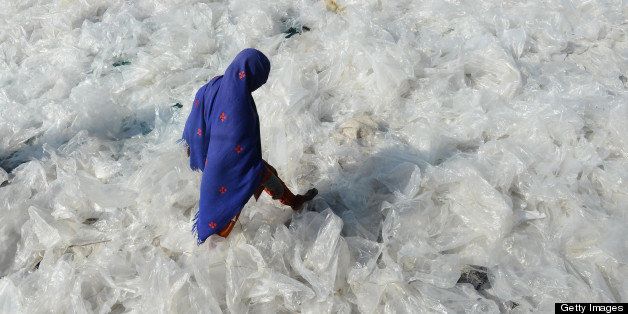 A Pakistan woman steps on recyclable plastic bags drying in the sun in Lahore on January 22, 2013. AFP PHOTO/Arif ALI (Photo credit should read Arif Ali/AFP/Getty Images)