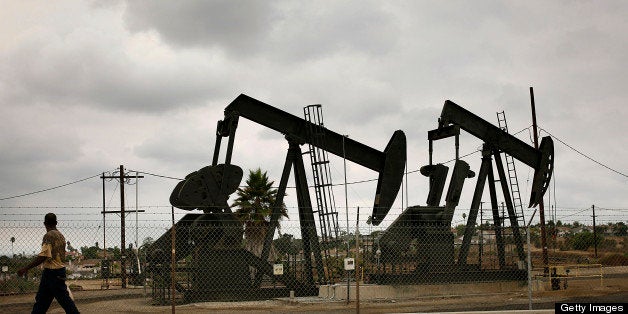 A pedestrian walks past pumpjacks operating at the Inglewood Oil field in Los Angeles, California, U.S., on Thursday, Oct. 19