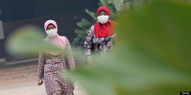 Two Muslim women wear masks as a haze covers Johor city in Johor Bahru, southern Malaysia on June 21, 2013. Malaysia was shrouded with smoky haze attributed to mainly fires burning on the Indonesian island of Sumatra causing 'unhealthy' levels of pollution in six areas. AFP PHOTO / DJANGO (Photo credit should read Django/AFP/Getty Images)