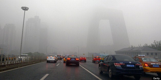 This picture taken on June 5, 2013 shows vehicles under heavy smog in Beijing. The capital has seen 46 smog days among the 100 days from January 1 to April 10, a record over the last 60 years, the National Climate Center announced. CHINA OUT AFP PHOTO (Photo credit should read STR/AFP/Getty Images)