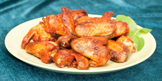 Chicken wings on plate. Freshly baked, selective focus. Green background..