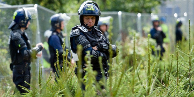 Police officers in body armour line the perimeter fence of the test drill site operated by British energy firm Cuadrilla Resources in Balcombe, southern England, on August 20, 2013, as anti-fracking activists hold a protest camp nearby. Environmental Protesters from the No Dash for Gas 'action camp' descended on the Cuadrilla operated site where they are testing drilling for oil to protest against the process of fracking and the exploitation of fossil fuels, after announcing two days of direct action. Hydraulic fracturing involves using huge amounts of pressurised water mixed with chemicals to crack open shale -- sedimentary rock containing hydrocarbons -- to release natural gas. Cuadrilla, which specialises in fracking for shale gas, is not currently using the technique at the test drill site in Balcombe. AFP PHOTO/Leon Neal (Photo credit should read LEON NEAL/AFP/Getty Images)