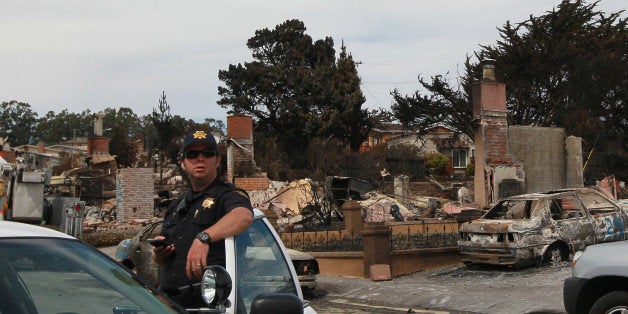 SAN BRUNO, CA - SEPTEMBER 13: A San Mateo County Sheriff deputy stands guard on a street devastated by fire following a dead