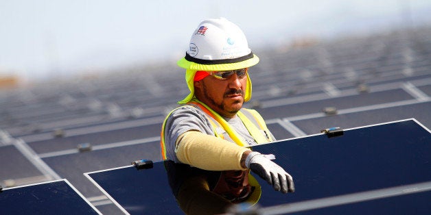 A worker installs First Solar Inc. photovoltaic solar panels at the Agua Caliente Solar Project in Yuma County, Arizona, U.S., on Wednesday, Feb. 16, 2012. Arizona will hold its Republican presidential primary on Feb. 28. Photographer: Joshua Lott/Bloomberg via Getty Images