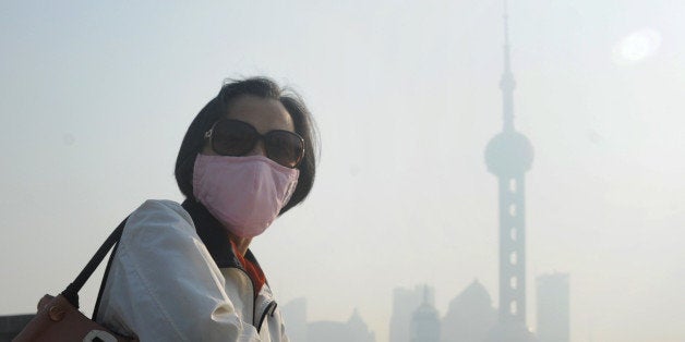 SHANGHAI, CHINA - NOVEMBER 07: (CHINA OUT) A woman wearing mask walks in highly polluted air at the Bund on November 7, 2013 in Shanghai, China. People were advised to stay indoors today as the Shanghai Environment Agency measured air pollution levels at five out of a possible six. (Photo by ChinaFotoPress via Getty Images)