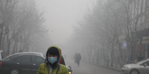 HARBIN, CHINA - DECEMBER 03: (CHINA OUT) A pedestrian wearing a mask walks along a road as heavy smog engulfs the city on December 3, 2013 in Harbin, China. Harbin Meteorological Bureau issued an orange warning on smog on Tuesday morning. (Photo by ChinaFotoPress/ChinaFotoPress via Getty Images)