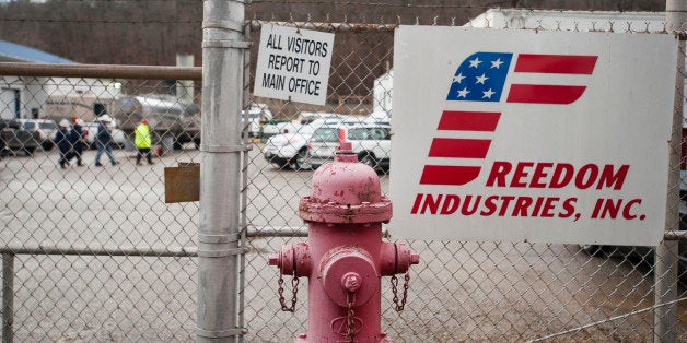 CHARLESTON, WV JANUARY 11, 2014:Workers walk behind the fence at the Freedom Industries building in CharlestonCharleston, West Virginia on Saturday, January 11, 2014. Around 5000 gallons of a chemical, used in the coal cleaning process, leaked into the Elk River from the West Virginia American Company and has stopped the usage of tap water for 300,000 West Virginia residents in nine different counties.Ty Wright for the Washington Post