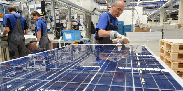 FREIBERG, GERMANY - AUGUST 14: A worker checks finished solar energy moduls at the Solarworld plant on August 14, 2013 in Fr