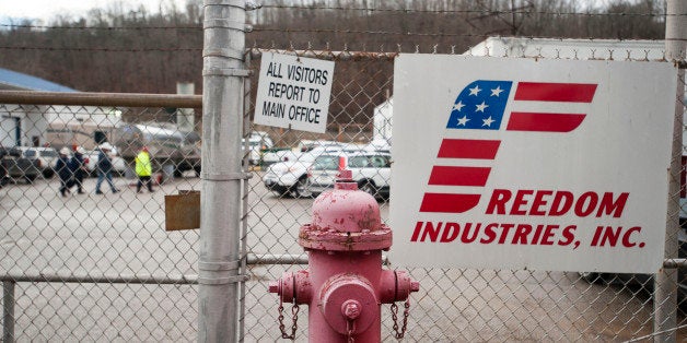 CHARLESTON, WV JANUARY 11, 2014:Workers walk behind the fence at the Freedom Industries building in CharlestonCharleston, West Virginia on Saturday, January 11, 2014. Around 5000 gallons of a chemical, used in the coal cleaning process, leaked into the Elk River from the West Virginia American Company and has stopped the usage of tap water for 300,000 West Virginia residents in nine different counties.Ty Wright for the Washington Post