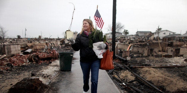 NEW YORK, NY - DECEMBER 07: Sheila Scandole recovers plants and an American flag for her boyfriend in the hard hit Breezy Point neighborhood on December 7, 2012 in the Queens borough of New York City. Breezy Point, home to many New York City firefighters and police, lost 111 homes in a fast moving fire during Superstorm Sandy with many more homes severely damaged from flooding. (Photo by Mario Tama/Getty Images)