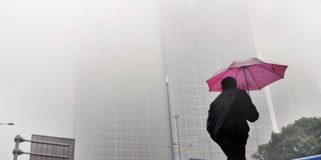 CHANGSHA, CHINA - FEBRUARY 24: (CHINA OUT) A man holding umbrella walks in the haze on February 24, 2014, in Changsha, Hunan Province of China. Altogether 1.43 million sq km of China's land territory, nearly 15 percent of the total, have been covered by persistent smog in recent days, according to news report. (Photo by ChinaFotoPress/Getty Images)